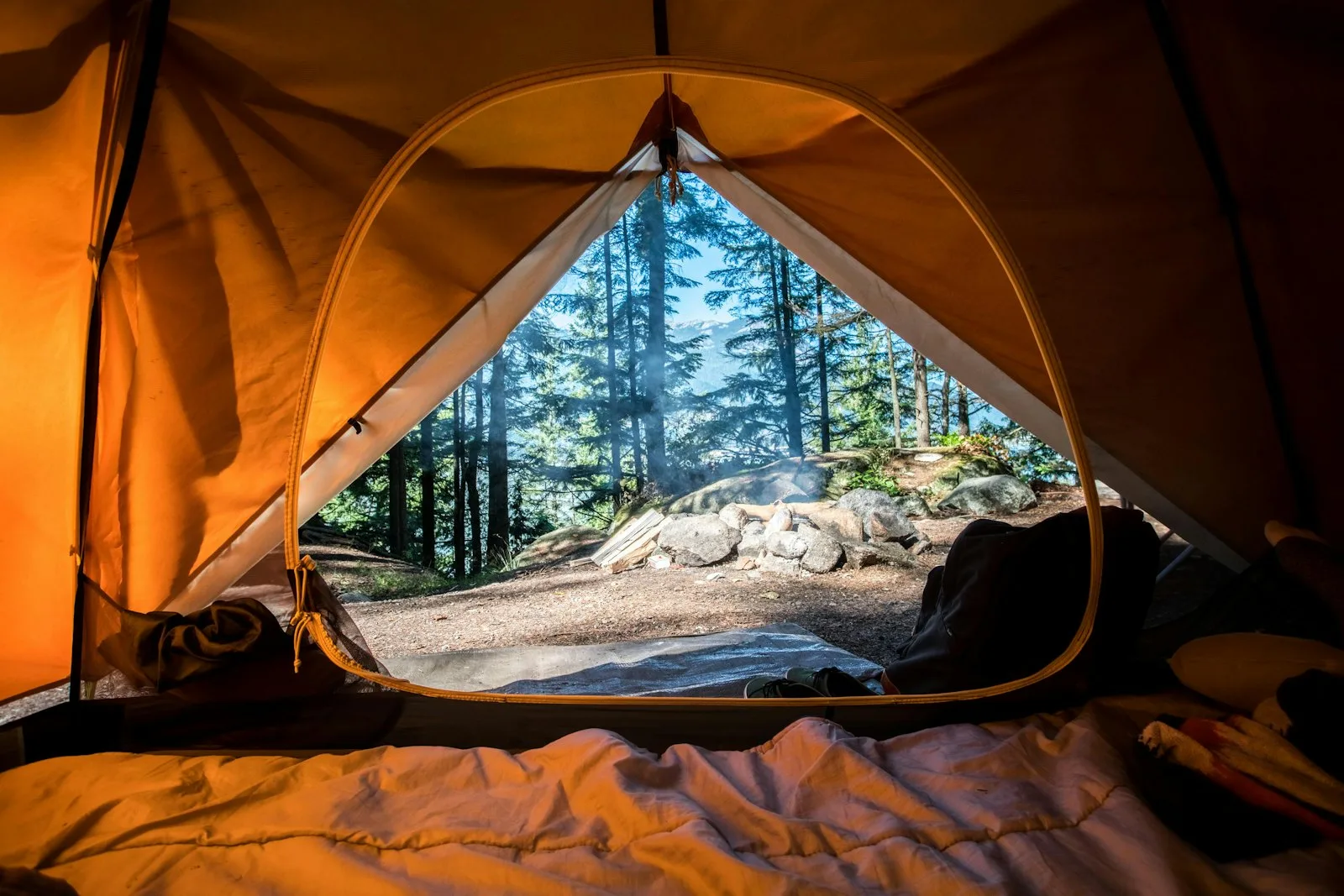 An orange camping tent among green trees